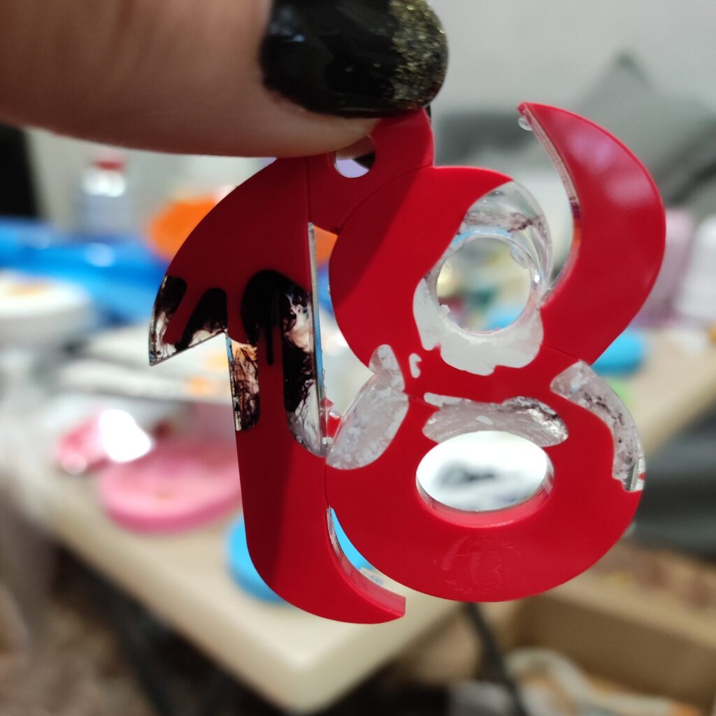Vista laterale di una lettera B rossa, con parti trasparenti e decorazioni dorate